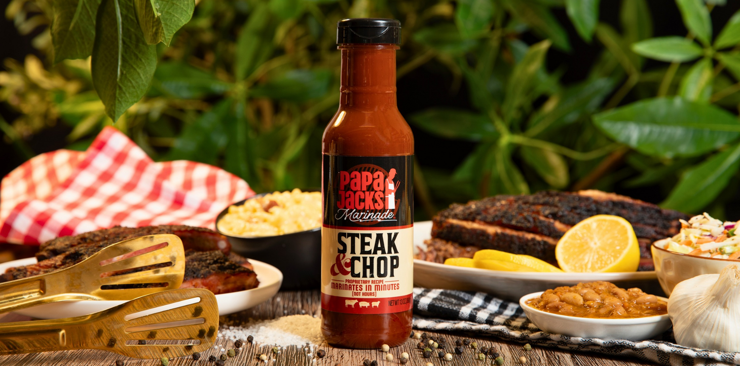 Papajohns Steak & Chop sauce bottle on a table with barbecue food and utensils.